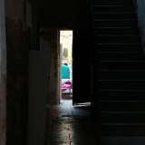 In un androne buio e poco curato intravediamo panni coloratissimi e uomini dalla carnagione scura